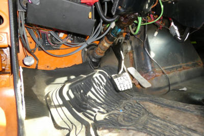 Truck cabin footwell with pedals and wiring harnesses visible under dash in a used 1999 International 2554 hooklift truck.