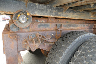 Truck chassis showing rusted undercarriage and suspension with wheel in view.