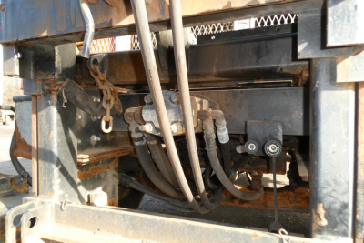 Industrial truck chassis showing hydraulic lines and valve block in a hooklift truck.