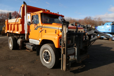 Orange International hooklift truck shown in side angle view with front forks and rear tooling visible