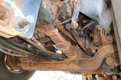 Truck suspension and drivetrain components with visible rust and dirt in engine bay undercarriage.