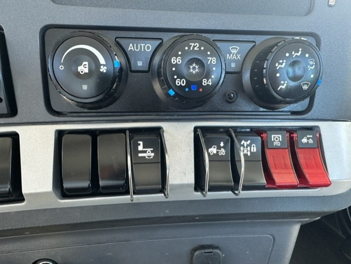 Kenworth T880 dashboard controls showing climate dials and switch panel with red toggles.