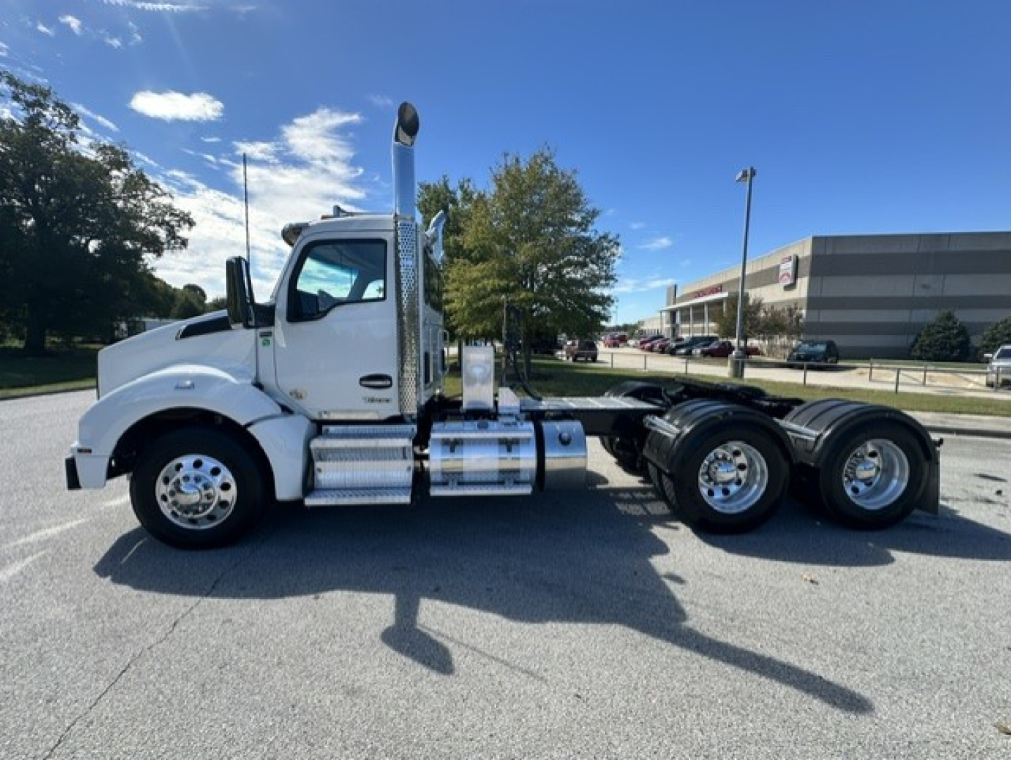 Kenworth T880 daycab tractor side view showing chrome exhaust stack, fuel tanks, and dual rear axles.