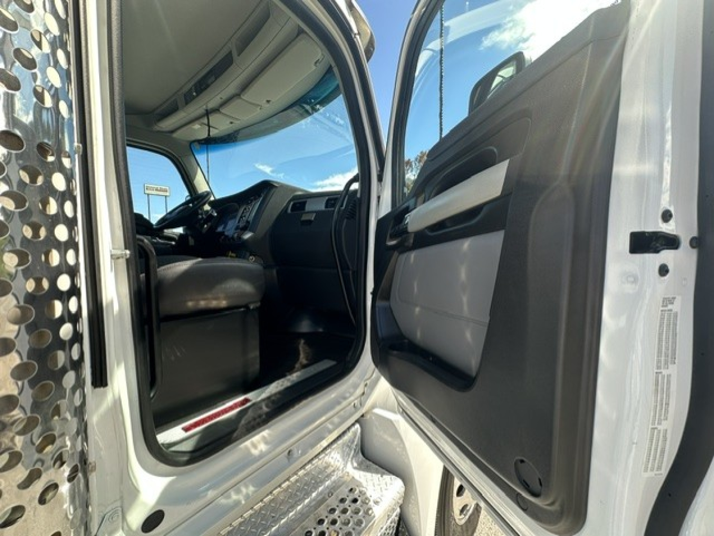 Kenworth T880 truck cab interior seen from open driver door with steps and dashboard visible, entry area and steering wheel in view.