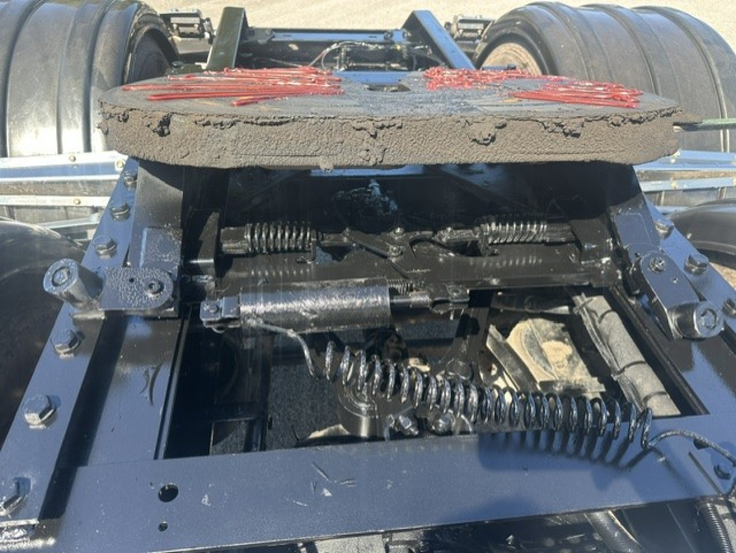 Kenworth T880 fifth-wheel articulation and suspension components showing circular air/dust cover, springs, and linkages underframe.
