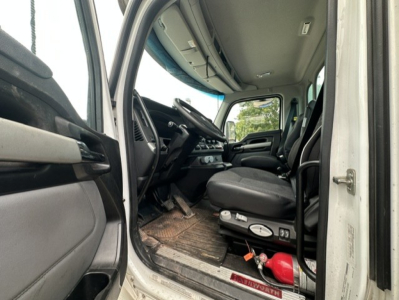 Kenworth T880 cab interior showing driver seat, steering wheel, and dash with floor mat and pedals.