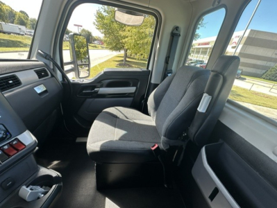Kenworth T880 cab interior showing driver and passenger seats with gray fabric, dashboard, steering wheel, and side window view.