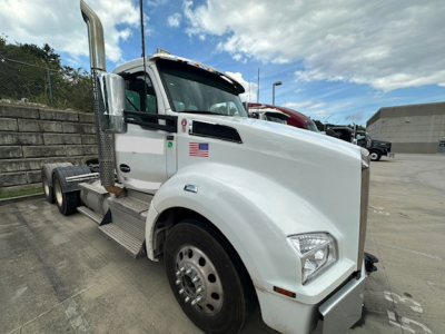Kenworth T880 conventional daycab truck in white with American flag decal and chrome exhaust stack.