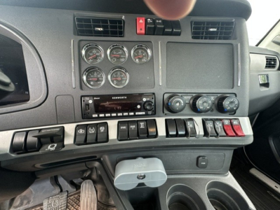 Dashboard panel of a Kenworth T880 showing multiple gauges, climate controls, Kenwood radio, and various switches.
