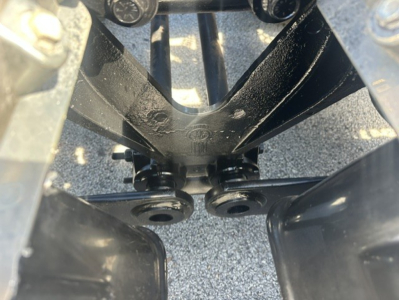 Kenworth T880 front frame rails and suspension mounting area seen from beneath showing hub and shackle attachments.