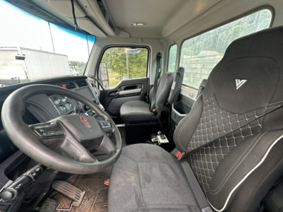 Kenworth T880 cab interior showing steering wheel, driver seat with diamond stitching, dashboard, and front passenger seat.