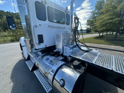 Kenworth T880 truck cab and chassis with shiny metal steps and fuel tank, side view showing rear of cab and mounting area for trailer connections.