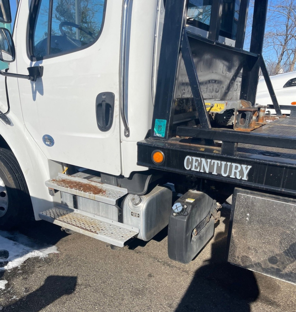 Tow truck side view showing cab with steps, metal platform, and Century branding on the bed of a 2019 Freightliner M2 106 Medium Duty tow truck.