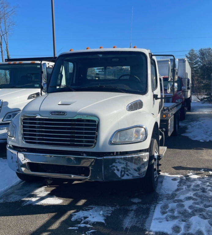 Truck front view of a white 2019 Freightliner M2 106 MEDIUM D tow truck showing chrome bumper grille, headlights, and side mirrors.
