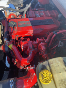 Engine bay of a 2019 Freightliner M2 106 medium duty tow truck showing a red Cummins engine with visible intake manifold and radiator cap