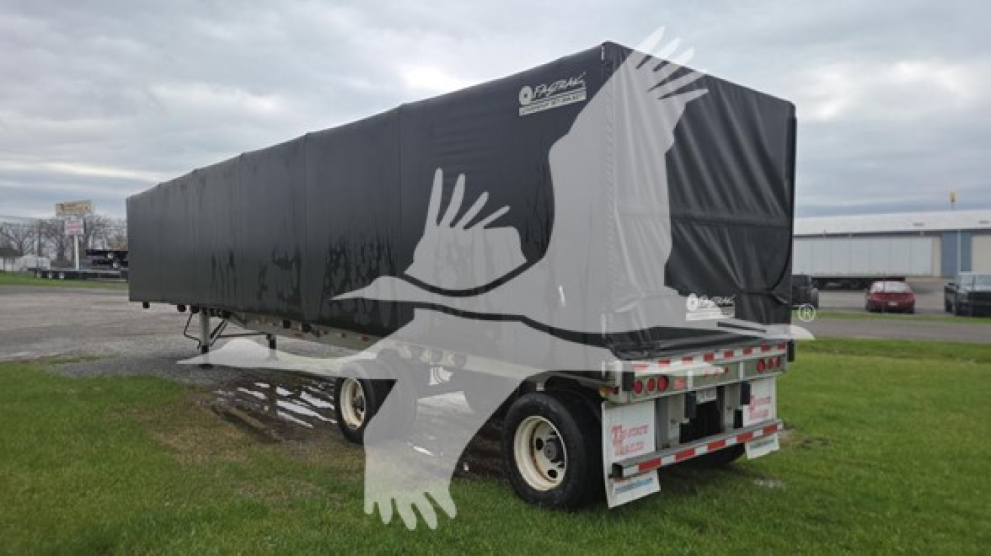 Curtainside trailer showing large white bird graphics on black tarp and rear bumper with reflective tape.
