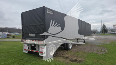 Trailer with black tarp covering sides, rear view showing tandem axles and curtain side with white logo and minimal text; appears to be a Reitnouer Big Bubba Conestoga curtain trailer.