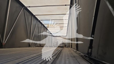 Curtainside trailer interior with ribbed metal floor and side rails, opening toward the rear, perspective shot.
