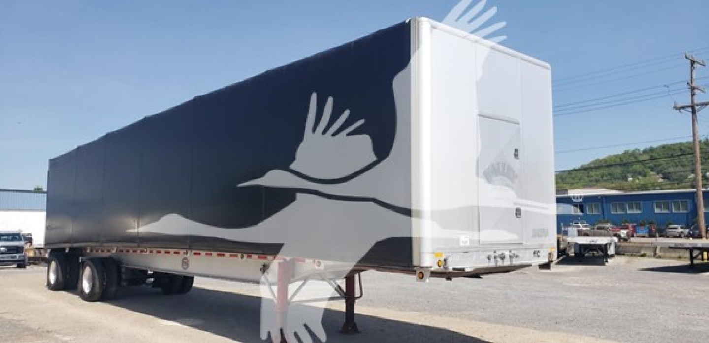 Mac aluminum flatbed trailer with curtainside, side view showing smooth silver aluminum panels and rear dual axles.