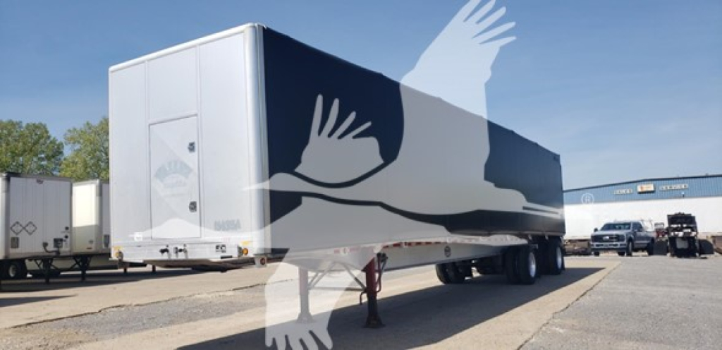 Mac aluminum flatbed trailer with curtain side in yard showing stock number 7685 and VIN visible on listing.