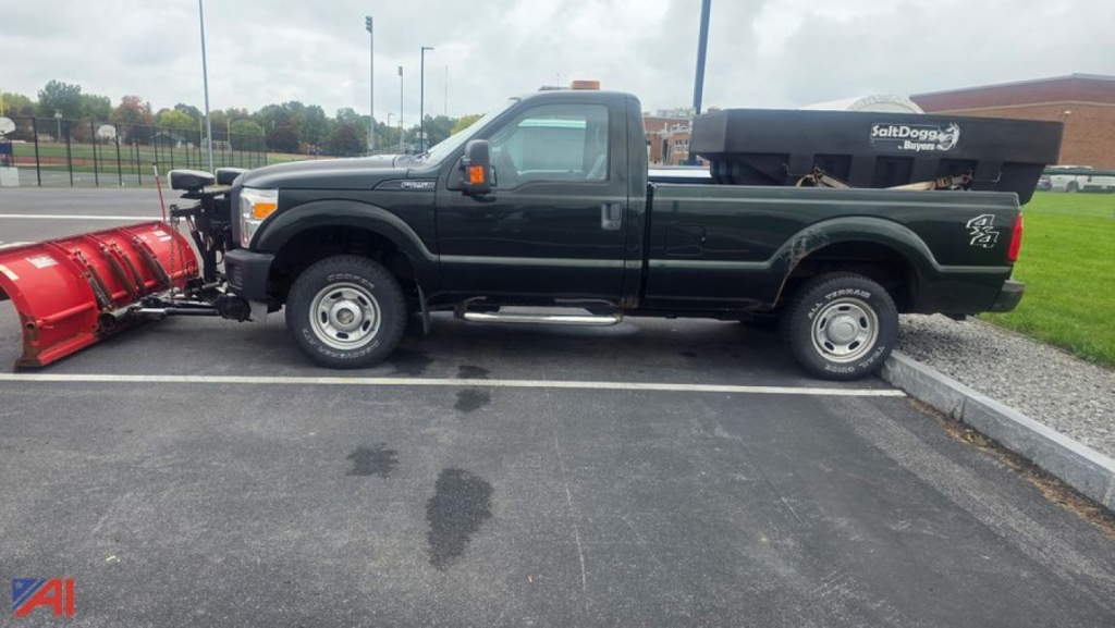 Ford F-250 Super Duty pickup with plow and salter in a parking lot, side view showing plow equipment and tool box