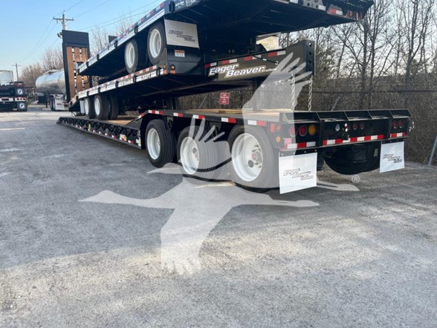 Trailer shown from rear-left angle with stacked lowboy trailer deck and multiple axles, Eager Beaver branding visible.
