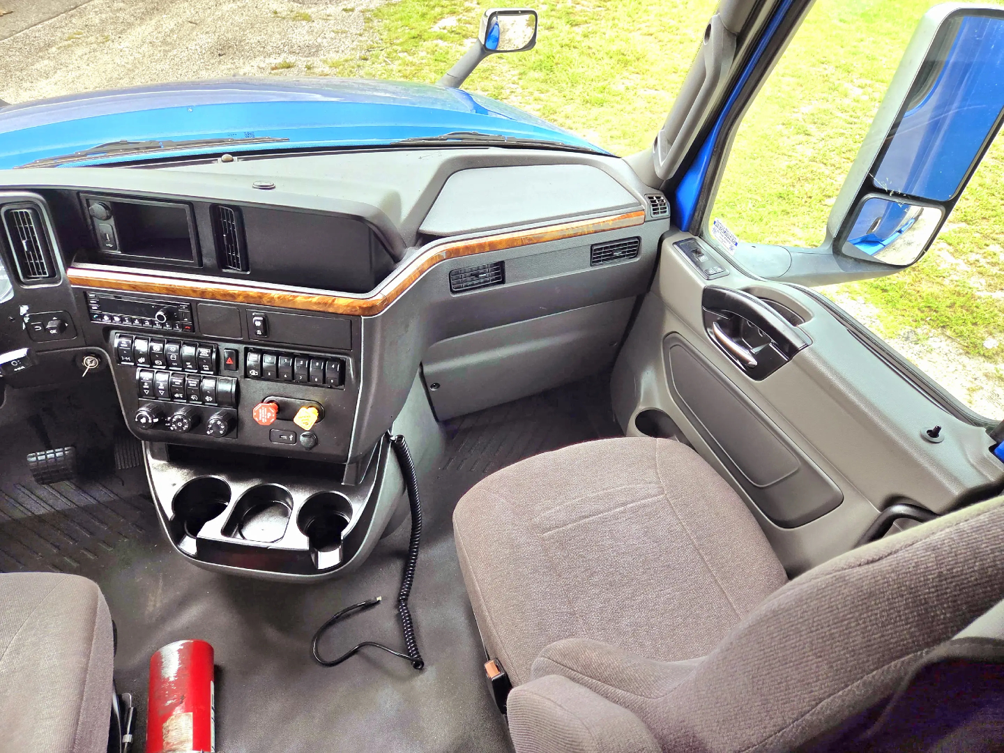 Interior view of a 2021 International LT625 truck sleeper cab showing dashboard controls, steering wheel, center console, and passenger seat.