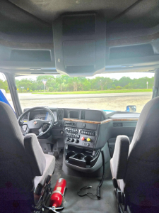 Interior cab view of a 2021 International LT625 truck showing steering wheel, dashboard controls, center console, and two front seats.