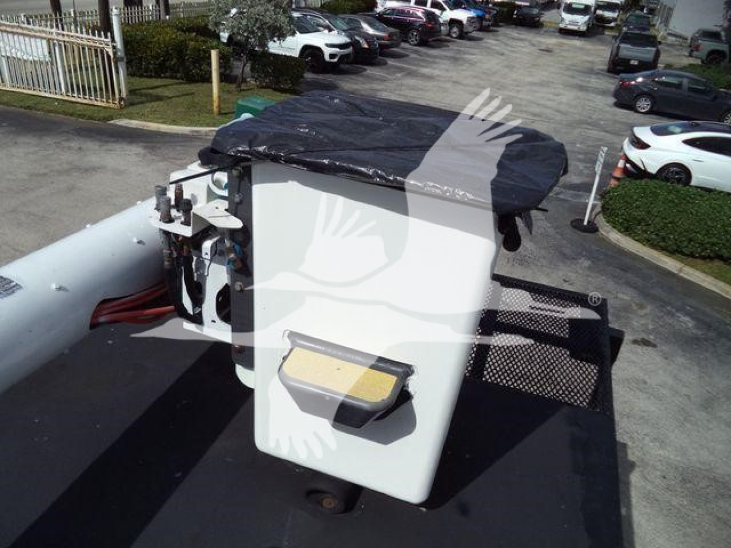 On a Ford F750 bucket truck, the equipment control box sits on the bucket with a white rectangular housing and a black cover. Visible text on the control panel labels is not legible.