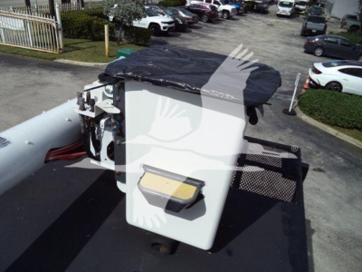 On a Ford F750 bucket truck, the equipment control box sits on the bucket with a white rectangular housing and a black cover. Visible text on the control panel labels is not legible.