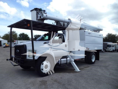 Ford F-750 bucket truck with crane-equipped boom, utility service body, front bumper guard, and two stabilizing outriggers extended.