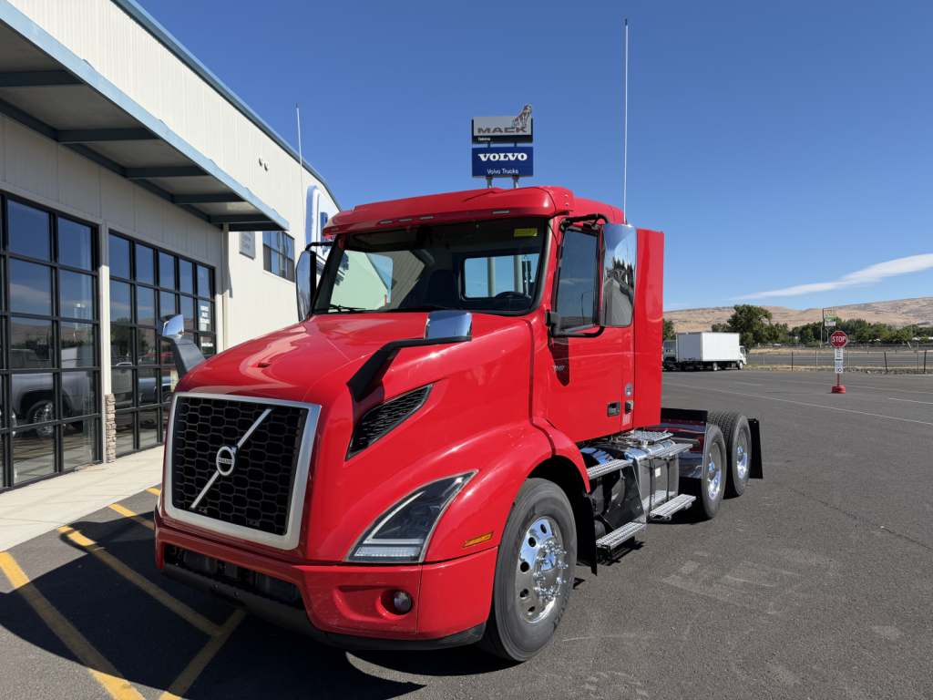Volvo VNR64T300 conventional daycab tractor in red, front three-quarter view, showing chrome grille, Volvo emblem, large headlights, and dual rear axles.