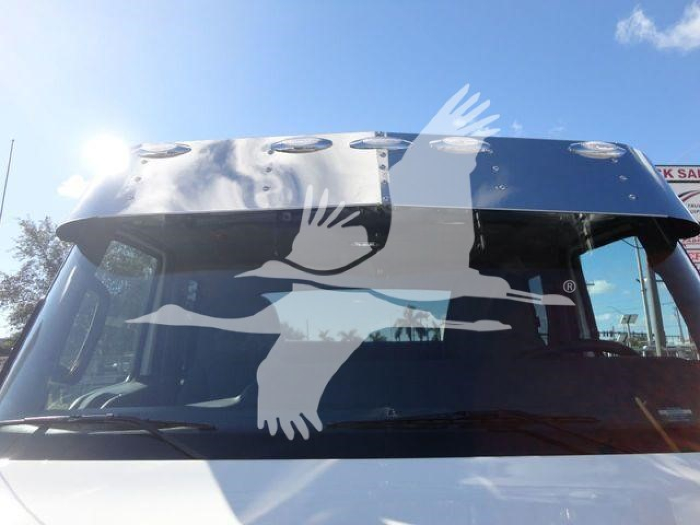 Truck cab windshield with decals of birds in flight and a hood-mounted ventilation hatch visible.