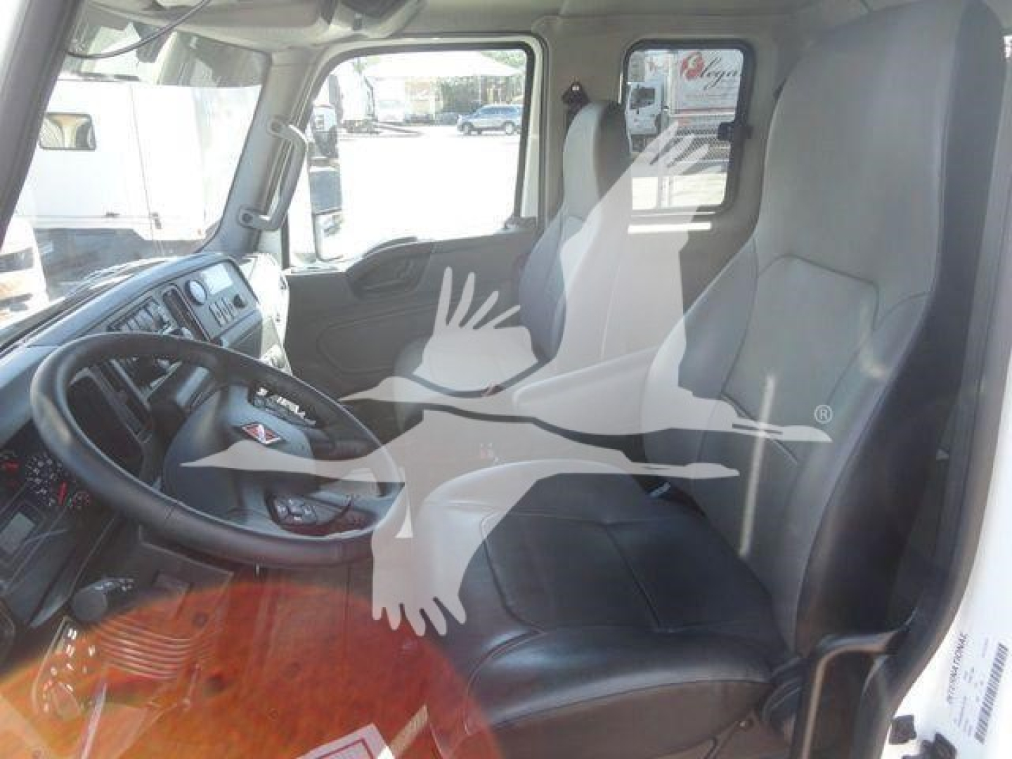 Truck interior showing driver seat and passenger seat in a new International MV cab with steering wheel and dashboard visible.