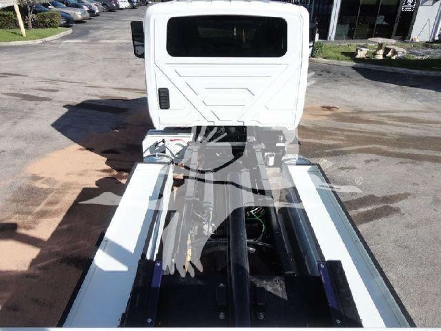 Tractor-trailer chassis with cab at rear, white truck cab seen from above, exposed drivetrain and rail system for coupling.