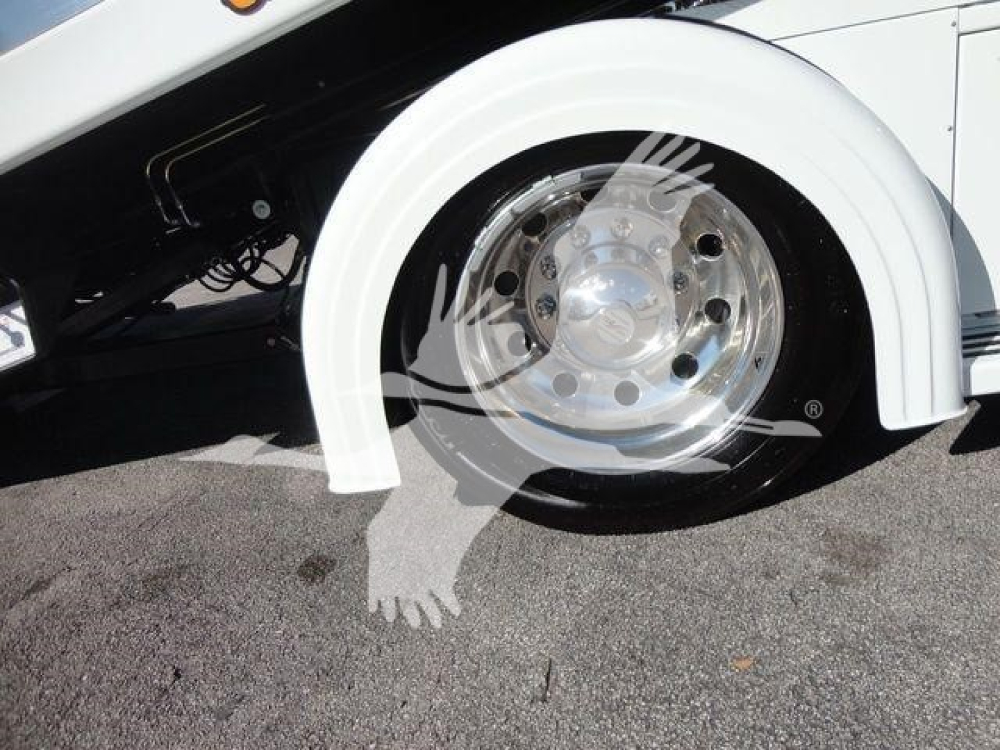 Wheel and front fender area of a white 2027 International MV truck showing chrome wheel with polished hubcap and part of the wheel arch.