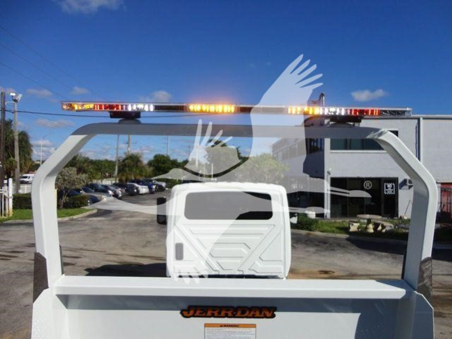 Tractor-style rollback truck rear view showing white frame with small cabin and amber warning lights on top. Vehicle logo 'JERDON' on rear bumper area.