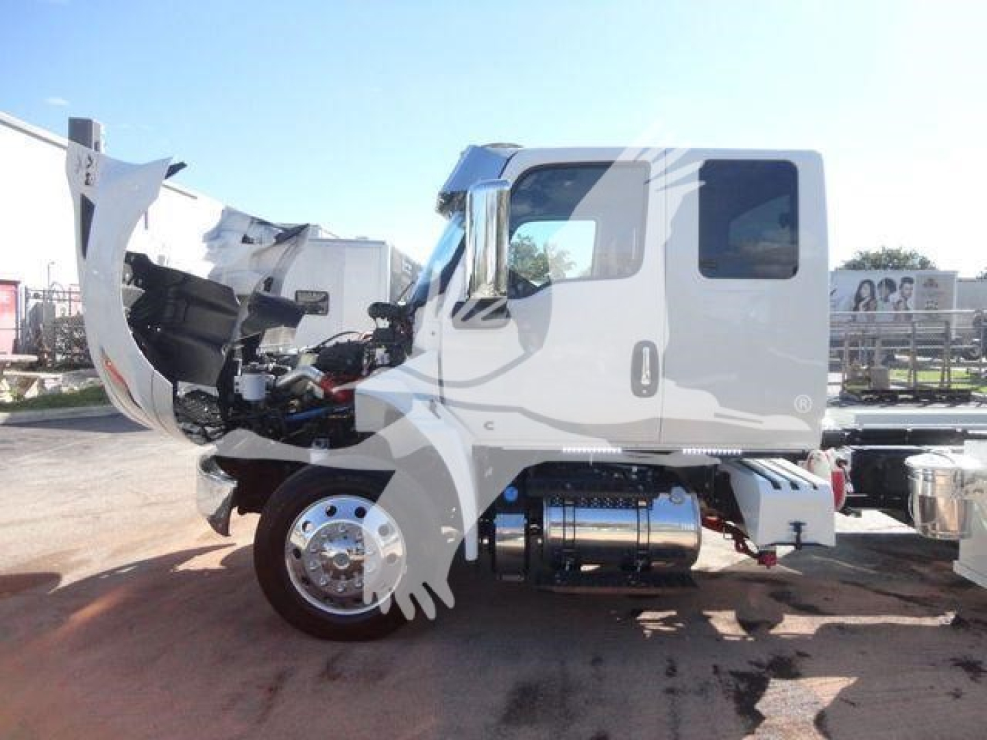 International MV truck cab with front hood open, showing engine bay and side chrome fuel tank; side view of cab, wheel, and chassis.
