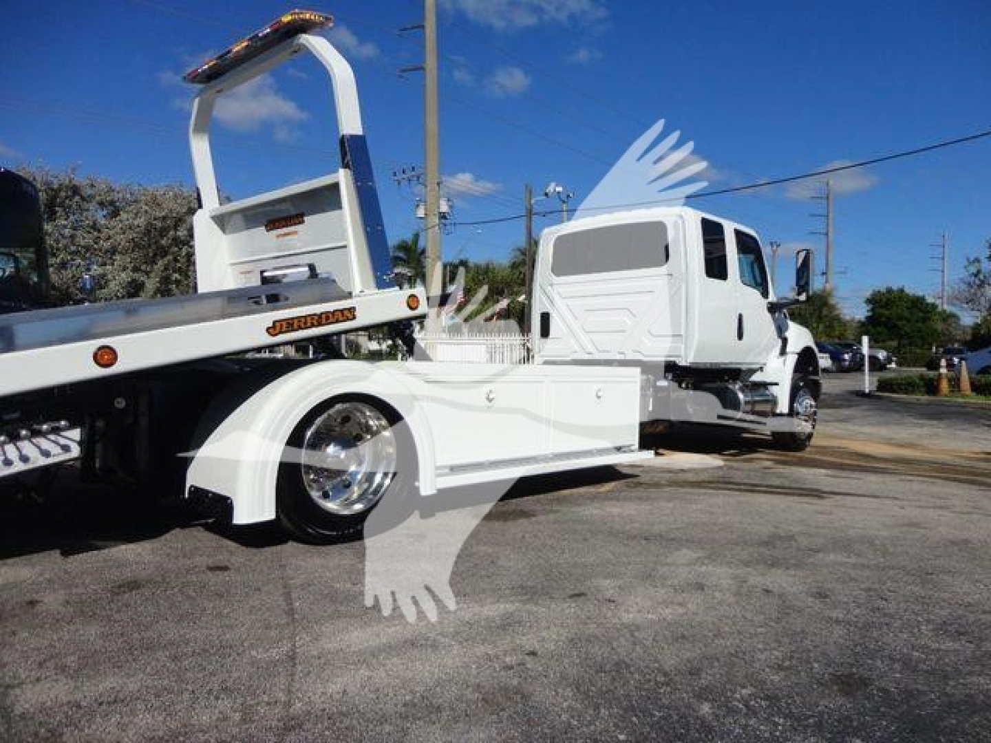 Truck with rollback tow equipment attached showing international MV cab and white tow truck platform.