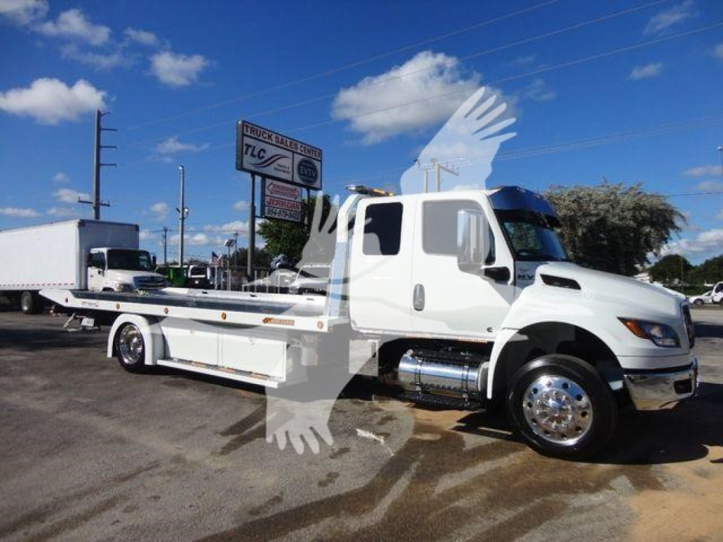 White International MV tow truck in a lot with a flatbed; visible text on signs in background and truck features but no readable model details