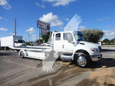 Tow truck flatbed on a white International MV with transporter bed and chrome wheels, side view, clear sky.