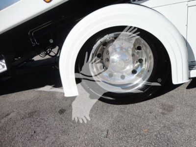 Wheel and front fender area of a white 2027 International MV truck showing chrome wheel with polished hubcap and part of the wheel arch.
