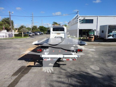 Rear view of an International MV rollback tow tractor on a lot, showing the flatbed and towing hitch assembly.
