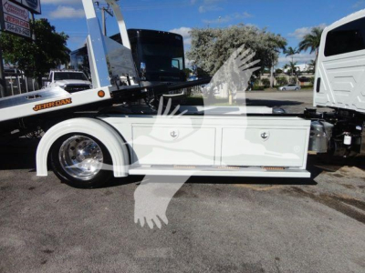 Truck body side view showing white tool/storage cabinet with two drawers and silver wheel well, on a rollback truck chassis.