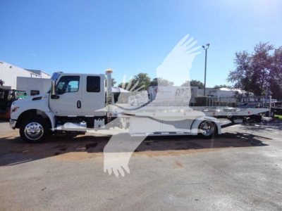 International MV rollback truck in-service with a white cab and a long flatbed, side profile visible.
