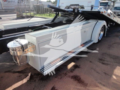 Trailer hitch show deck with white toolbox/storage box and cylindrical chrome fuel/air canister mounted at front, International MV chassis in background.
