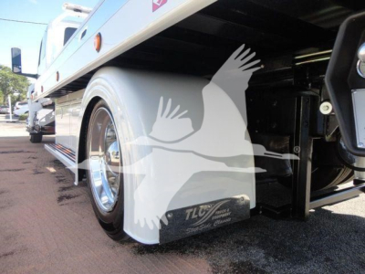 Truck side undercarriage view showing wheel, mudflap, and TLC badge on fender with chrome rims.