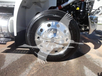 Wheel and front tire of a white International MV truck showing polished alloy rim and tire details.