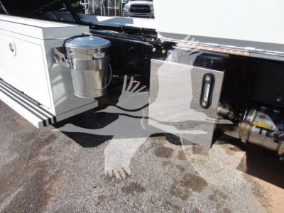 Truck side with cylindrical fuel/wuel filter canister and metal toolbox; panel with a small vertical gauge or switch and hydraulic lines; reflection of watermark.