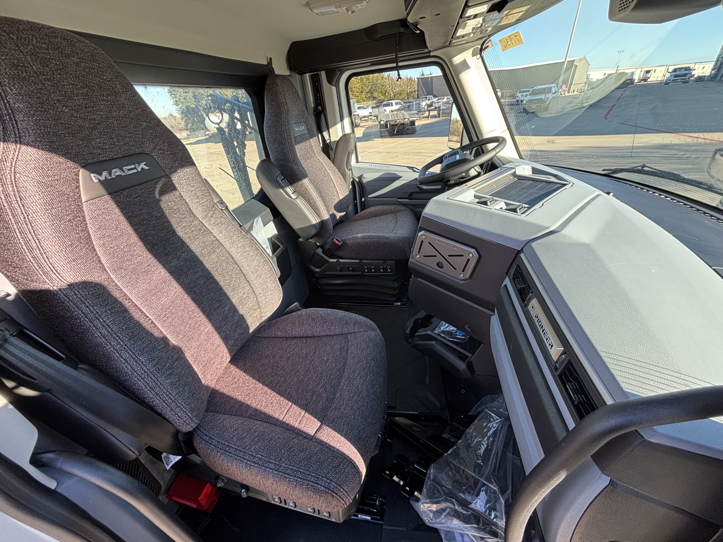 Interior of a new 2027 Mack PR64T daycab truck cab, showing driver and passenger seats, steering wheel, dashboard, and center console.